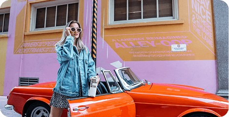 A vintage orange sports car parked by a colourful wall